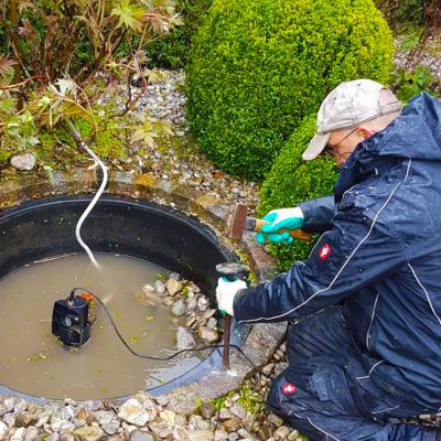 Ein Mitarbeiter löst eine einbetonierte Wasserwanne mit Meisel und Hammer.