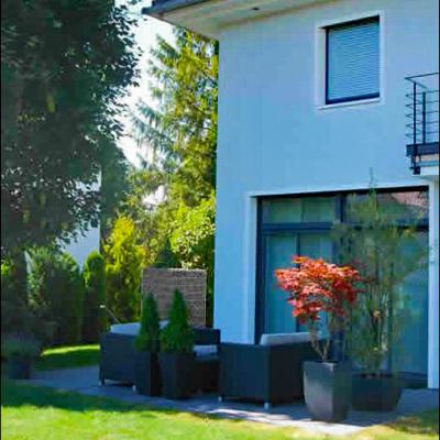 Eine Terrasse im Schatten mit schwarzen Gartenmöbel und dezenter Bepflanzung.