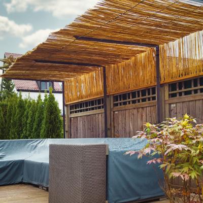 Ein Sonnenschutz aus Bambusmatten (ca. 5 mtr.) über einer abgedeckten Gartengarnitur.