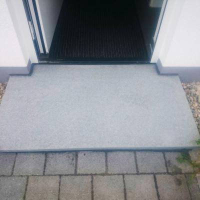 Ein Eingang zum Haus mit einer großen grauen Granitsteinplatte.