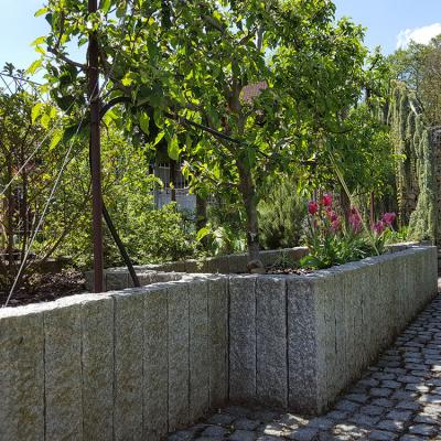 Ein großes 1 mtr. hohes bepflanztes Pflanzenbeet mit Naturstein.