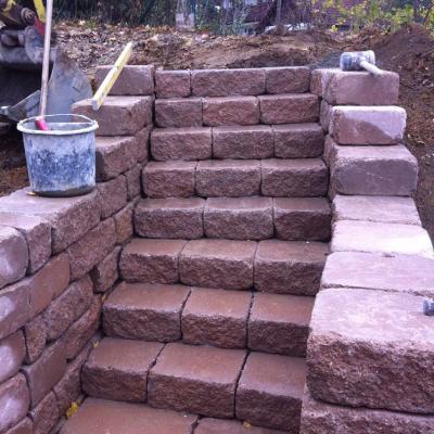 Neunstufige Treppe aus rötlichem Naturstein. Leicht rund.